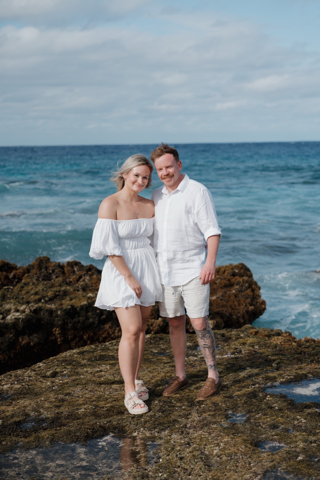A couple standing together on volcanic rock above the sea